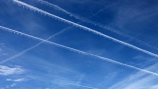 contrail wispy white clouds against a blue sky.