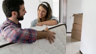A young couple unbox and move a new memory foam mattress they bought from Amazon during the prime day deals event