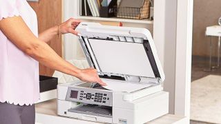 Best printers headline image showing someone pulling a freshly-printed page off a Brother printer