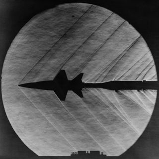 A photo taken in 1962 captures supersonic shock waves as they pass over a scale model of the American X-15 hypersonic plane.