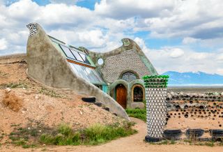 Earthship community in Taos showing colourful off grid homes nestled into the desert earth