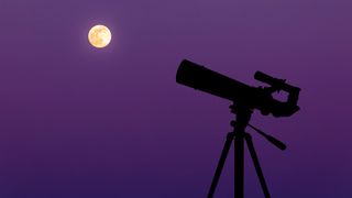 Silhouette of a telescope pointing towards a full moon.