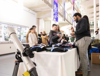 a man stands behind a table handing out swag to kids