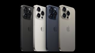 Four colour variations of iPhone 15 Pro standing in a line on a black background
