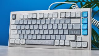 The NuPhy Nos75 mechanical keyboard on a stone surface with a blue background