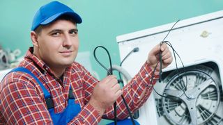 A plumber replacing a washing machine's drive belt