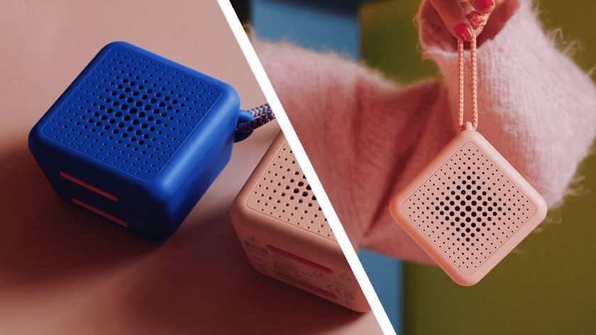 The pink and blue versions of IKEA&#039;s Vappeby Bluetooth speakers, on a pink table and being held on a string