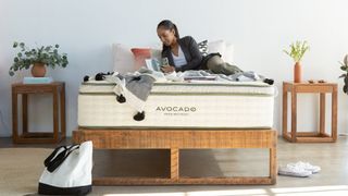 A woman lies on the Avocado Green Mattress while reading a magazine