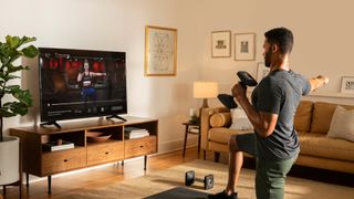 Man doing a Peloton strength training workout with dumbbells at home