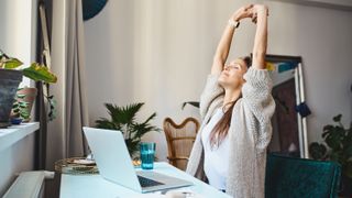 a woman stretching at her desk 