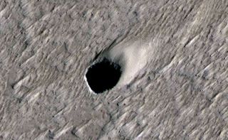 A grayscale scene with a rocky-looking surface (viewed from an above angle) and a dark pit.