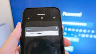 The iPhone's Remote app shows a redacted password in the foreground while the password entry screen appears on a TV connected to the Apple TV 4K (2022) in the background.