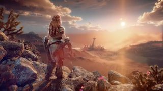 Aloy standing on a hillside looking out to a sunset landscape