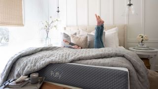 A happy woman lying on top of a duvet on her Puffy Mattress