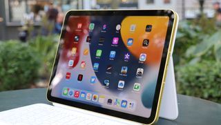 iPad 10.9 (2022) pystyasennossa pöydällä vihreää pensasaitaa vasten