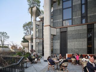 Detail of terrace with diners and the concrete tree planters in the background at Thomas Heatherwick's 1000 Trees development in Shanghai