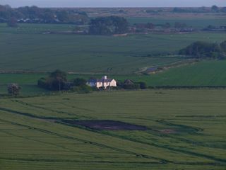 A house in the distance surrounded by fields