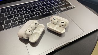 AirPods 3 and AirPods Pro 2 in cases on an open Apple MacBook laptop