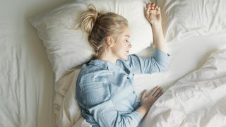 A woman lies in bed looking peaceful and relaxed