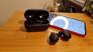 Sony WF-1000XM4 earbuds and case next to an iPhone