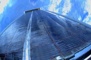 Photo from a spacewalking astronaut of newly installed solar array on the international space station, with earth in the background.