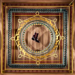 An Hermès boot emerges from the carving in one window