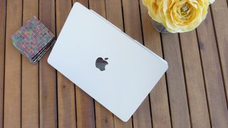 Top down photo of the MacBook Air 13 M3 open slightly on a slatted table with the lid facing the camera