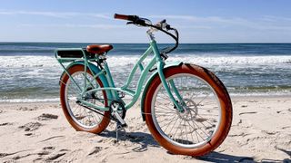 A sea foam green ebike on the beach.