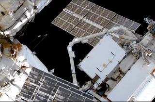 Russian cosmonauts Sergey Prokopyev and Dmitry Petelin (at right) watch as a large radiator is moved from the Rassvet mini-research module to the Nauka multipurpose laboratory module by the European Robotic Arm during a April 18-19, 2023 spacewalk outside of the Russian segment of the International Space Station.