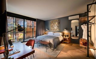 Bedroom with white linen and a gray throw. There is a study unit and two bedside tables and a wooden floor. Sliding doors leading to the balcony.