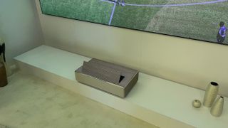 Samsung The Premiere 8K projector on a shelf projecting a football match onto a screen