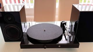 Pro-Ject Juke Box E1 on a table, with two speakers