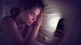 A woman uses her phone in bed at night