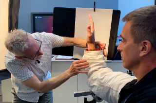 Award-winning photographer Dennis Murphy, co-founder of My Hand My Causes, poses former astronaut Chris Cassidy's hand.