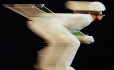 Blurred image of skier in white on black background, illustrating best skiwear