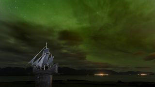 green auroras over a harbor and a boat monument