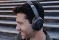 JLab Lux wireless headphones being worn by a man with dark hair