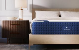 The image shows a DreamCloud memory foam mattress on a pale wood bedframe