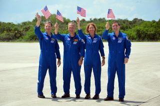 NASA’s final space shuttle crew waves American flags celebrating their Fourth of July arrival at Kennedy Space Center for their launch on July 8, 2011. From left to right: Commander Chris Ferguson, Pilot Doug Hurley and mission specialists Sandy Magnus and Rex Walheim.