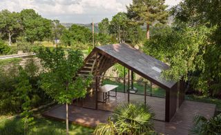 writer's cabin made of undulating wood outside Madrid