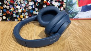 Navy blue Sony WH-CH720N headphones lying on a wooden surface.