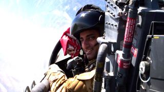 an astronaut in a jet cockpit looking over his should in the middle of a flight