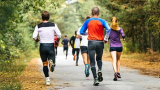 a photo of a group of runners running through a park