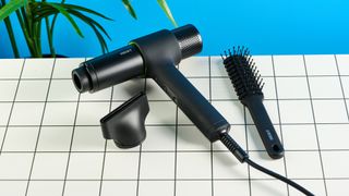 the heist 3.0 men's hair dryer in black with a bright green ring and magnetic attachment photographed against a blue background 