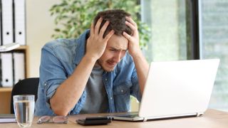 Man looking confused whilst sitting in front of a laptop