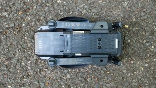 The underside of the folded Holy Stone drone folded in on tarmac surface.