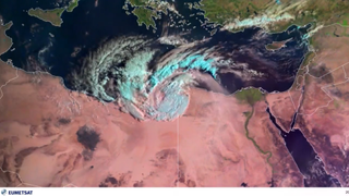 a swirling storm is seen from space over brownish desert and the blue waters of the mediterranean sea.