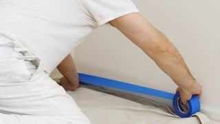 Man applying masking tape for drop cloth