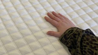 During our Eve Premium Hybrid mattress review, our lead mattress reviewer places her hand on the top cover to see how warm or cool it feels