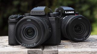 Panasonic Lumix S5 IIX camera in outdoors on a table in front of the Panasonic Lumix S5 II